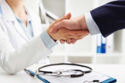 photo of physician shaking hands with business person